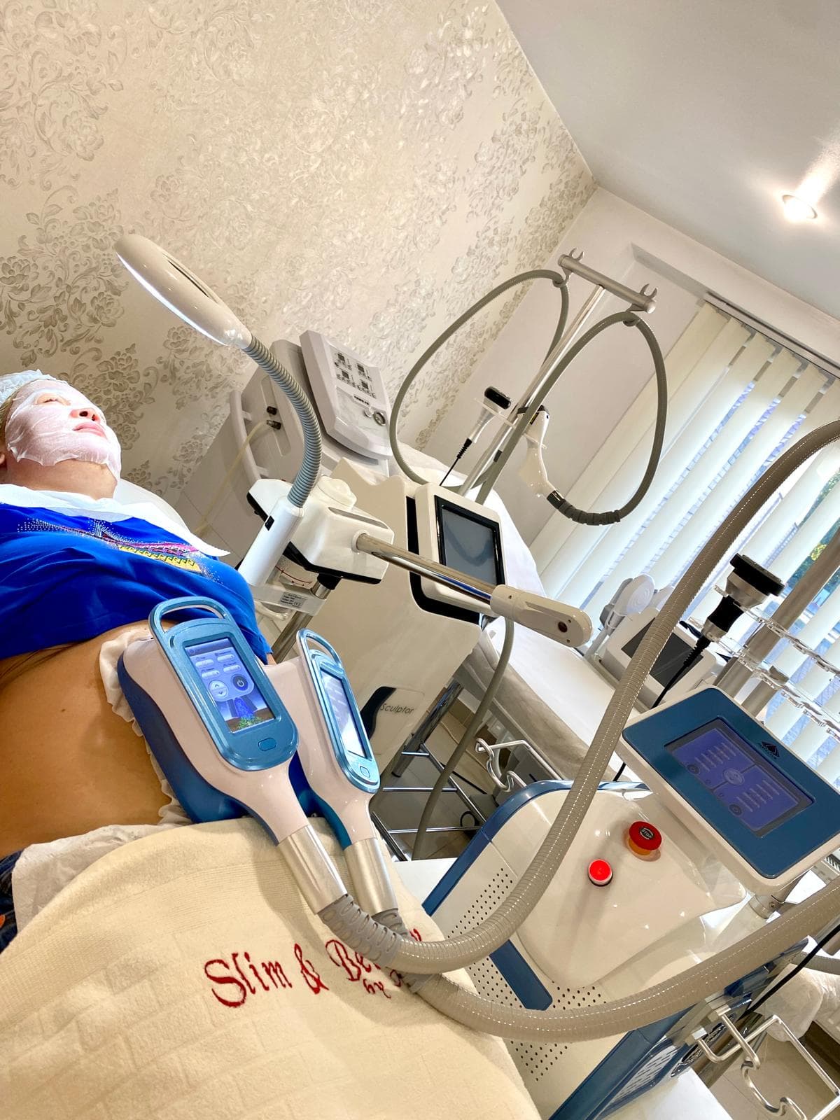 Clientă întinsă în timpul unei ședințe de criolipoliză, cu aplicatoarele pe abdomen